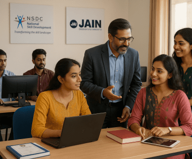 Indian students learning job-oriented skills in a classroom with NSDC and Jain University banners, guided by a professional mentor at DMC Finishing School Pvt. Ltd.